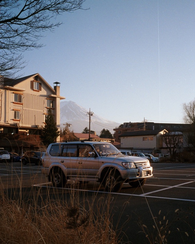 SUV parked in a lot at sunset, with a mountain rising behind neighborhood houses.