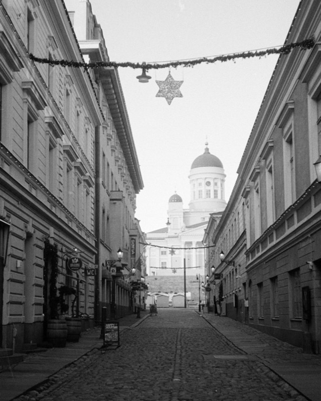 Empty cobblestone street leads to a domed cathedral, with a star decoration overhead.